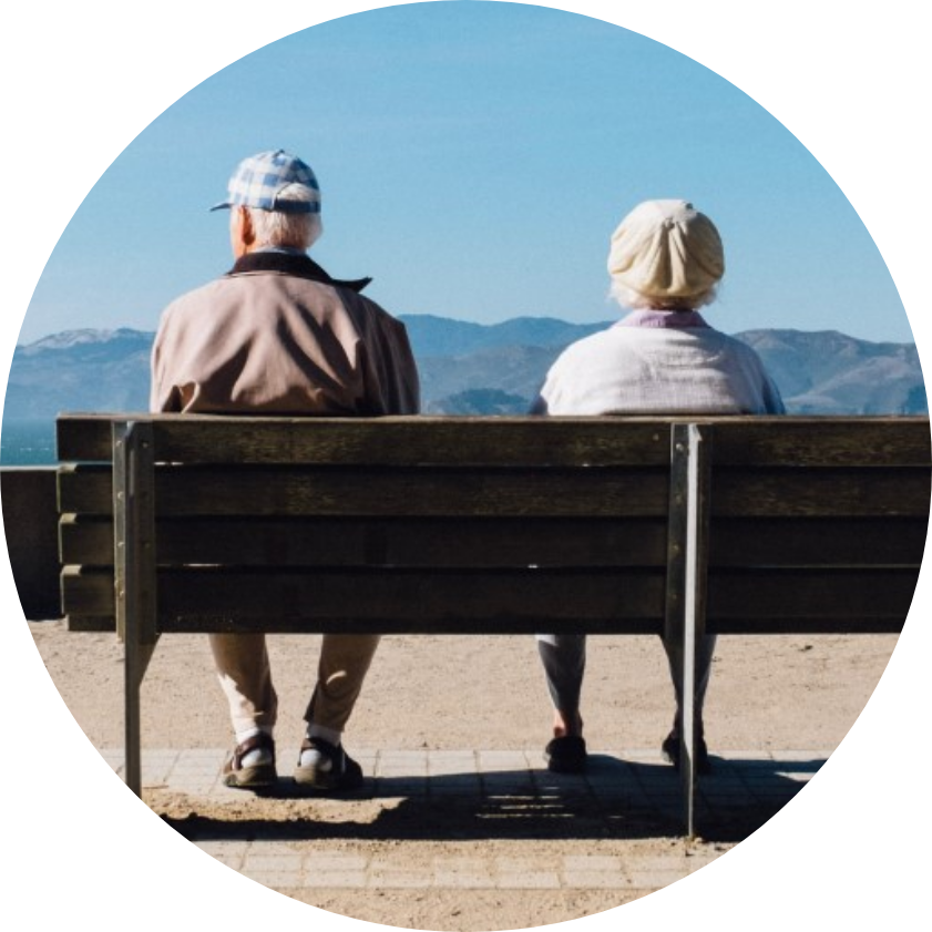 Retired couple sitting on bench together with mountains in background